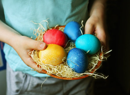 Celebration of Easter. The child holds a small basket of colorful dyed eggs.