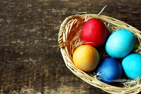 Easter background.Easter colorful painted eggs lie in a basket on a wooden surface. The view from...