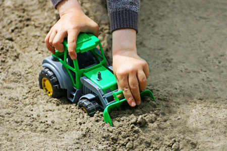 Stroll. In the image of the hand of a child who plays with a green toy car in the sand .の写真素材