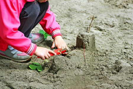 The child plays on the Playground in the warm season. The child plays with sand and plants.の写真素材
