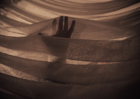 Hand in the Light touching fabric, orange, brownの写真素材