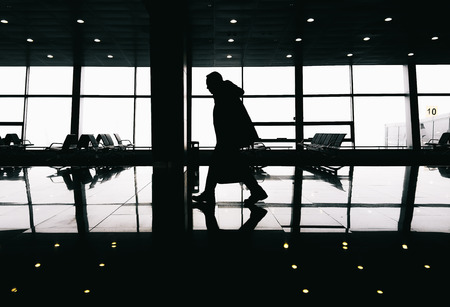 Silhouette of man walking in modern buildingの写真素材