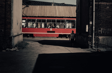 Red tram emerging from shadow streetのeditorial素材