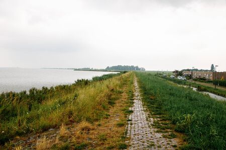 Rainy weather on the sea, where the coastline with green grass is visibleの写真素材