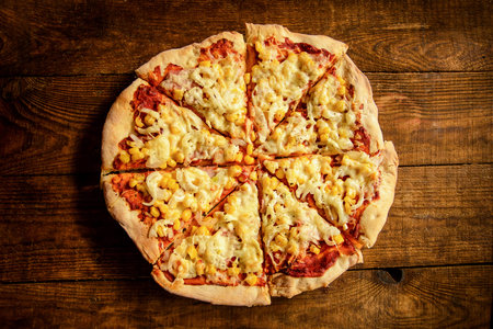 pizza cooked at home-made is cut into pieces and lies on a wooden table