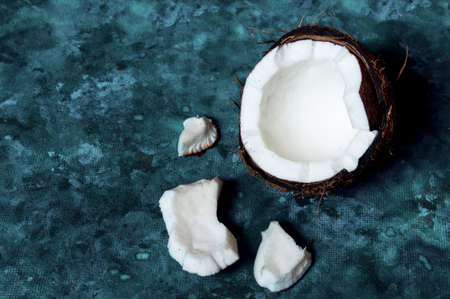 Open coconut lies on a dark blue background next to broken pieces lying randomlyの写真素材