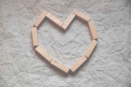 background of crumpled craft paper with wooden rectangles laid out in the shape of a heart in a minimalist styleの写真素材