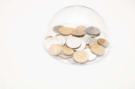 metal coins are grouped under a glass semicircle on a white backgroundの写真素材