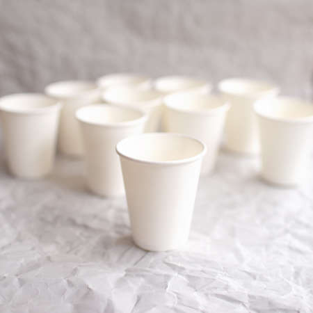 disposable cups made of white paper are laid out on gray crumpled paper in a geometric patternの写真素材