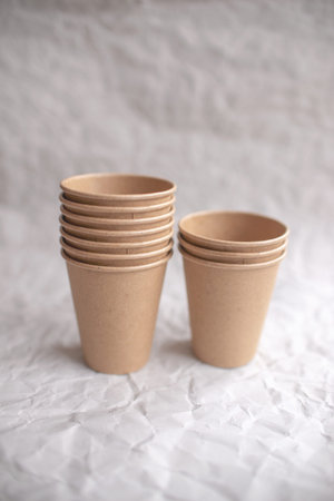 disposable kraft paper cups laid out on gray crumpled paper in geometric pattern