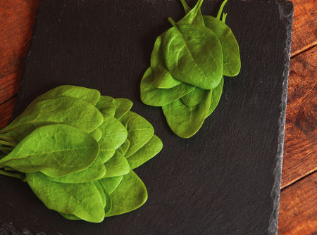 bright green fresh spinach lie on a black serving board