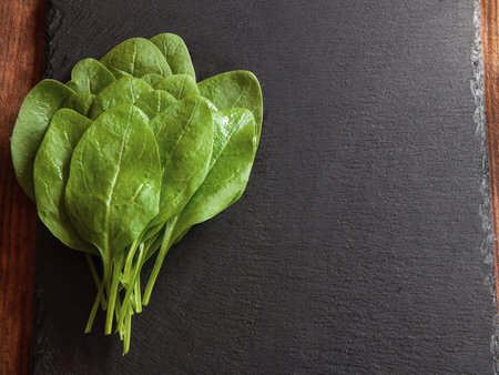 bright green fresh spinach lie on a black serving board