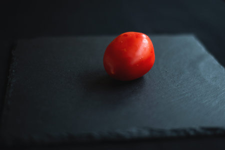 tomato is cut in half, rests on a black board for serving in the middle
