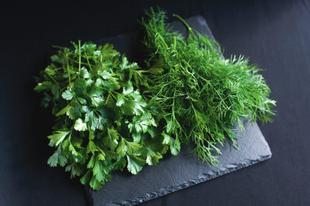 fresh dill and parsley lies on a black boardの写真素材