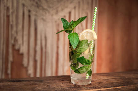 Mojito summer citrus cocktail with lemon and mint. Cold lemonade with lemon on a brown wooden table.の写真素材