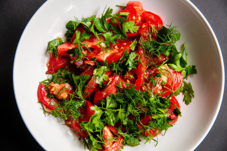 Parsley tomato and dill salad on a white plate. Healthy food for weight loss, vegetarian food. Fresh vegetables cut in a dish.の写真素材