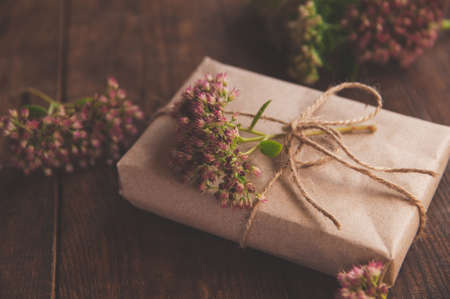 Homemade wrapped Present on a wood table. Close-up image of beautiful gift box decorated with flowersの写真素材