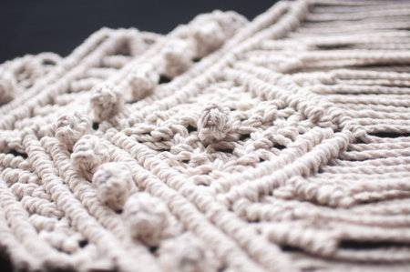 Macrame ornament from white natural cotton threads on a black background. Hand weaving from yarn on...