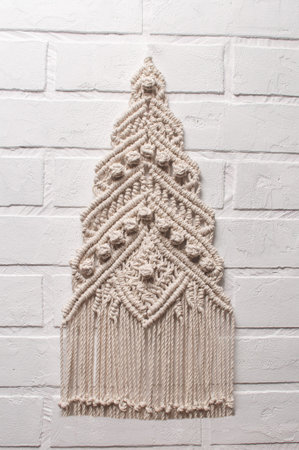 Christmas tree ornament macrame from white natural cotton threads on a white background. Festive...