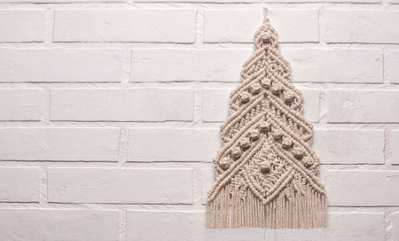 Christmas tree ornament macrame from white natural cotton threads on a white background. Festive...