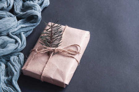 Gift box next to vintage runner gray on black background, festive composition on dark paper