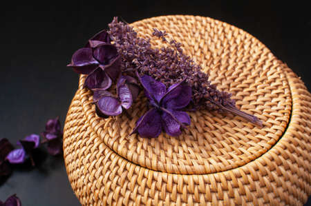 woven straw box craft round top with dried flowers and lavender on black backgroundの写真素材