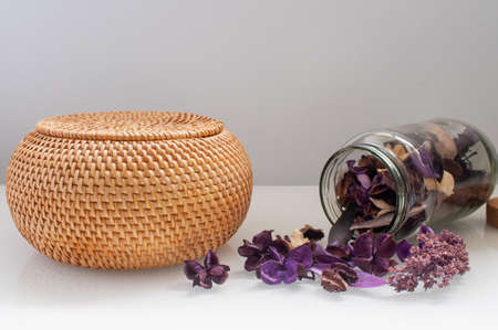 wicker straw box craft round on top with dried flowers and lavender on a white backgroundの写真素材