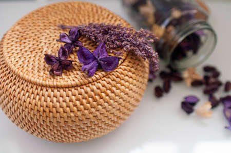 wicker straw box craft round on top with dried flowers and lavender on a white backgroundの写真素材
