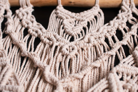 fragment of a wall decor made of woven threads in the style of macrame on a black background
