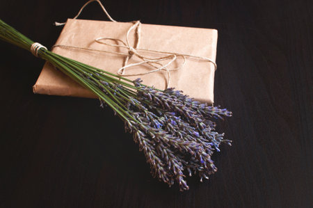 Craft paper gift box with fresh flowers on a black background.の写真素材