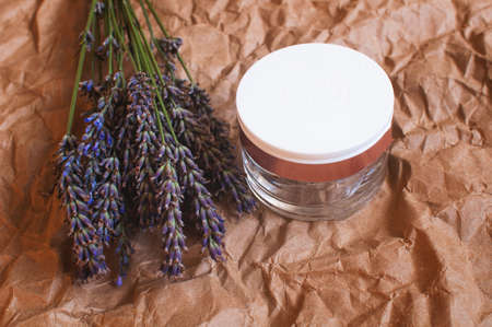 jar of cream with a bouquet of fragrant fresh lavender flowers on a background of brown kraft paperの写真素材