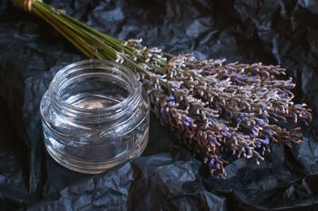glass jar with transparent gel and fresh lavender flowers on a black background.の写真素材