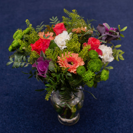 floristic bouquet of red gerberas, carnations and greenery in a glass vase, professionally madeの写真素材