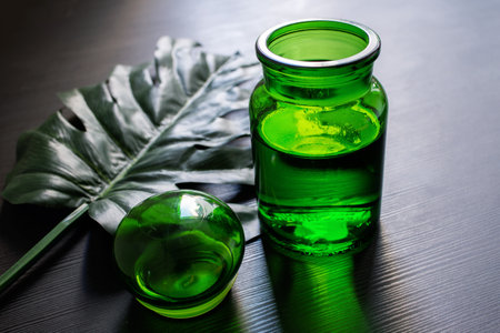 Monstera leaf on a black background with a green vase. Concept and minimalism.の写真素材
