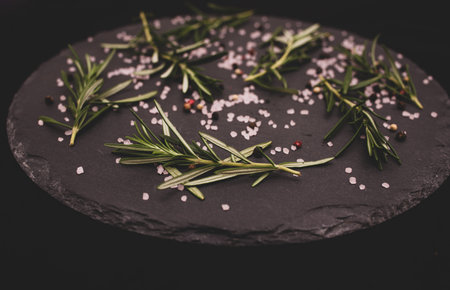 Fresh rosemary with sea salt and pepper on a black background.の写真素材