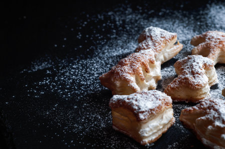 Cream puff pastry with powdered sugar on a black background. Selective focus.の写真素材