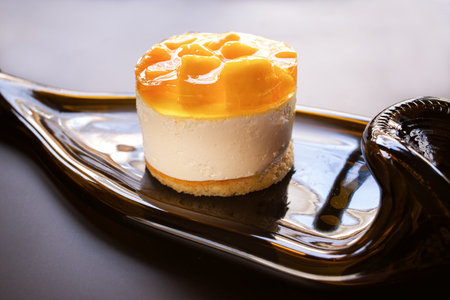 Mango tart soufflÃ© cake on a lined plate made from a wine bottle gray background