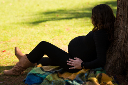 Pregnant woman at park in warm weather with green grassの写真素材