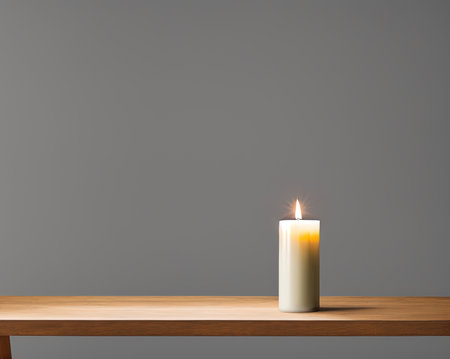Burning candle on a wooden table in front of a gray wallの写真素材