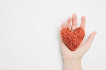 Orange knitted heart in a female handの写真素材