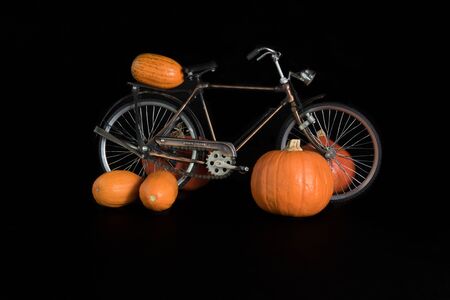 Pumpkins, bicycle and a jute bag on a black backgroundの写真素材
