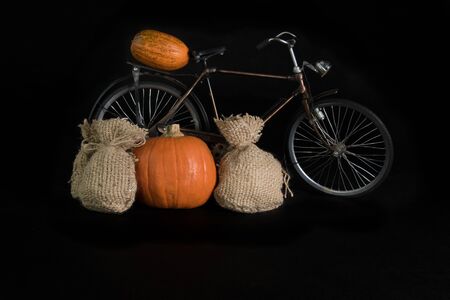 Pumpkins, bicycle and a jute bag on a black backgroundの写真素材