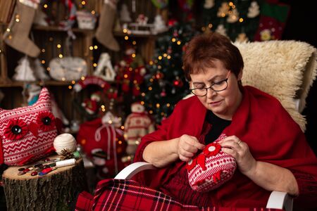 Grandmother sews a plush owl in Christmas arrangementの写真素材