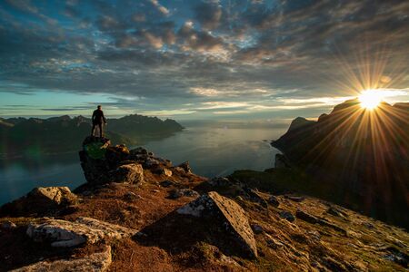 A wonderful sunset over a fjord in northern Norway with a man in the backgroundの写真素材