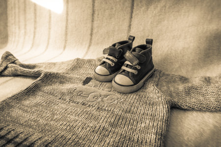 Baby sweater and sweet boys' shoes on the bed. Home