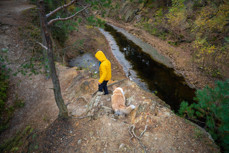 A little child is standing on the edge of a cliff, there is a small lake below. polish mountains.の写真素材