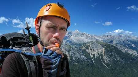 A thirsty tourist drinks water through a tube against the backdrop of an amazing panorama of the mountains in the Dolomites. Dolomites, Italyの写真素材