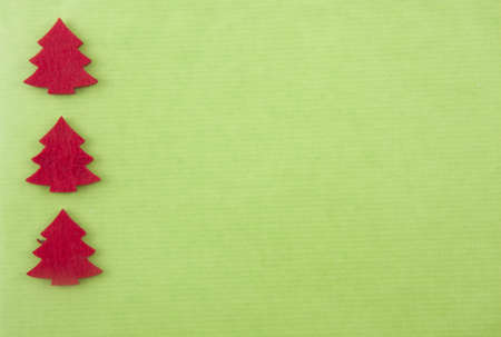Christmas background with three red felt christmas trees on bright green paperの写真素材