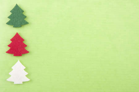 Christmas background with felt christmas trees in green, red and white on bright green paperの写真素材