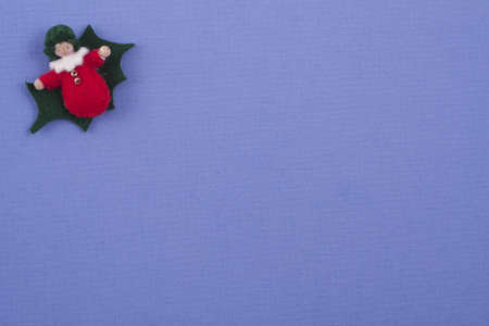 Greenand red colored felt christmas figure on deep purple colored paper の写真素材